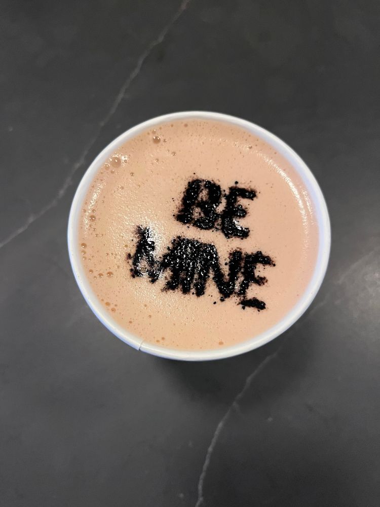 latte foam with “be mine” in cocoa powder
