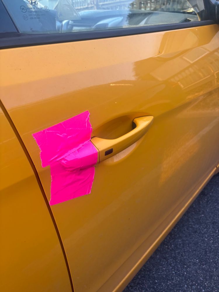 Yellow car taped up with pink duct tape
