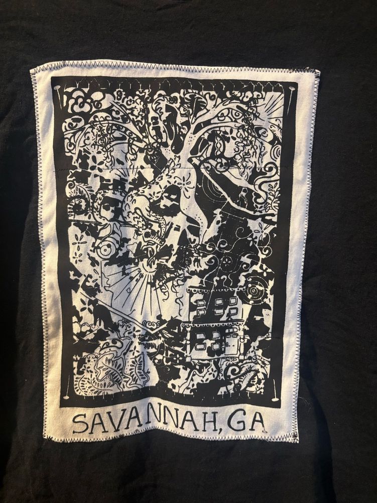 Screen printed black/white patch machine-sewn on a shirt. The design is of intricately intertwined motifs found around the city Savannah, Ga. In the center there is a dragon shaped like a live oak tree that branches out into the rest of the piece 