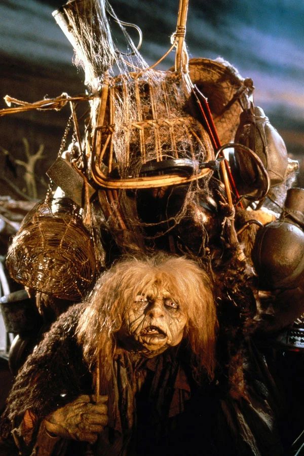A Muppet from the movie Labyrinth. An old woman with very wrinkled skin and wiry white hair and ragged clothes. She is bent over beneath an enormous pile of junk on her back.