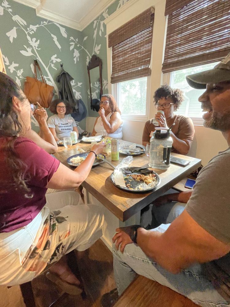 A photograph of ~6 educators conversing around a dining table.