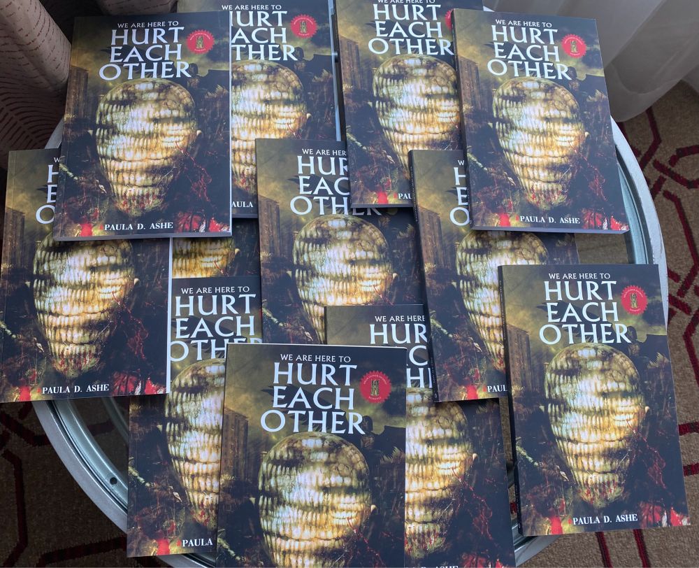 A stylish pile of copies of my book, We Are Here to Hurt Each Other