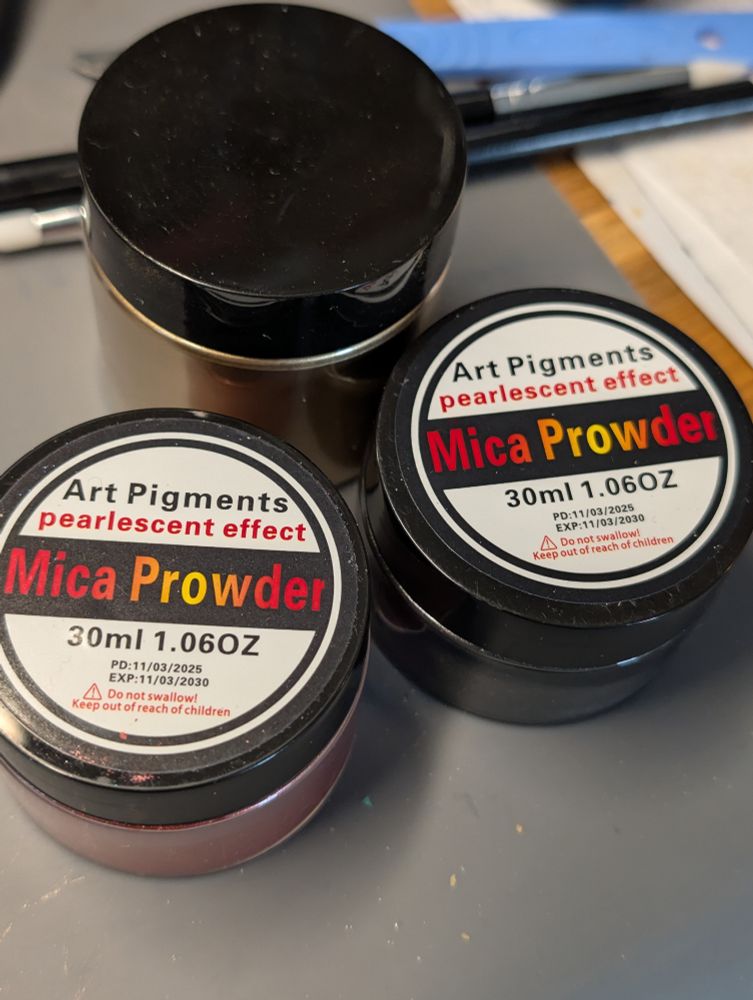 Image of three pots of pearlescent mica pigment, sitting on a grey work mat. On the lid of the pigment the word "Powder" is incorrectly spelt "Prowder", this applies to all of the colour range.