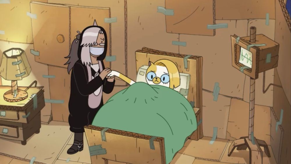 A screenshot of a dream segment from Fionna and Cake Season 2 Episode 6. Cake the Cat is pregnant and sitting in a hospital bed in a room made of cardboard. M-Cron is tending to her.
