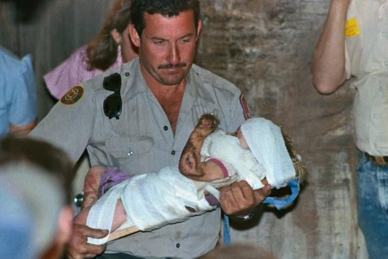 Rescuer holding a baby wrapped in bandages