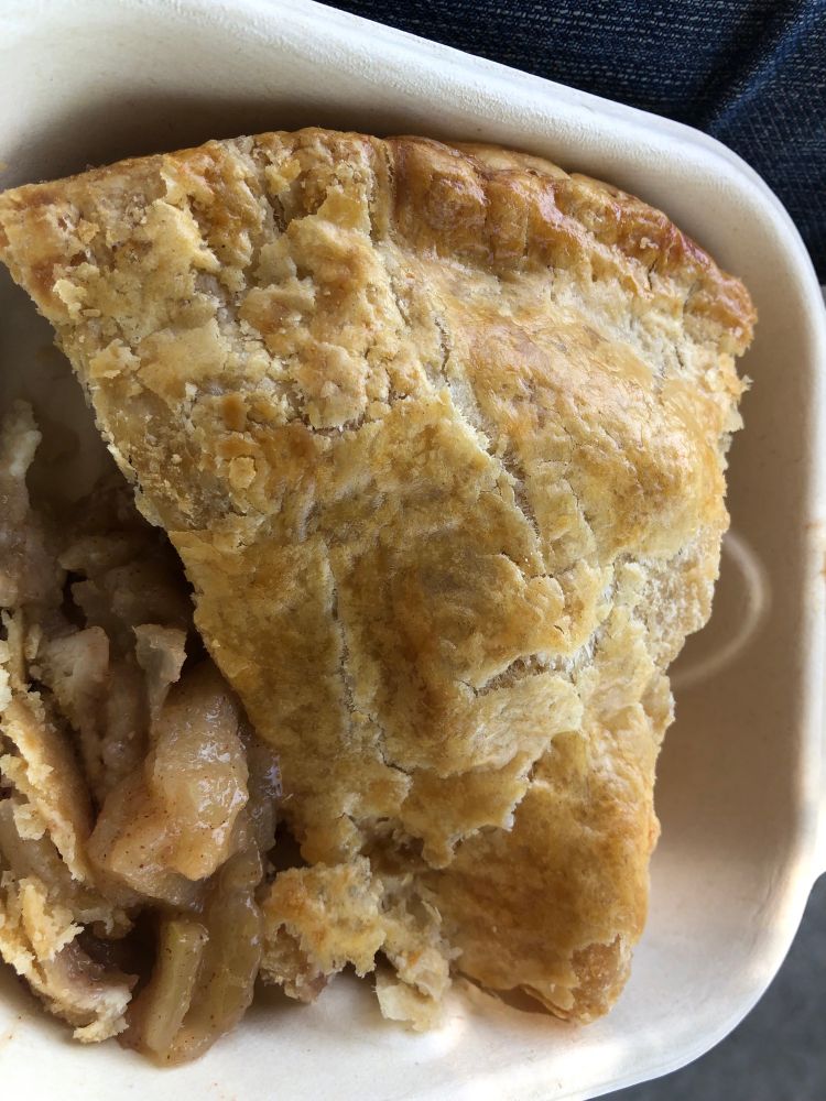 Image description: a slice of apple pie in an open cardboard to-go box 