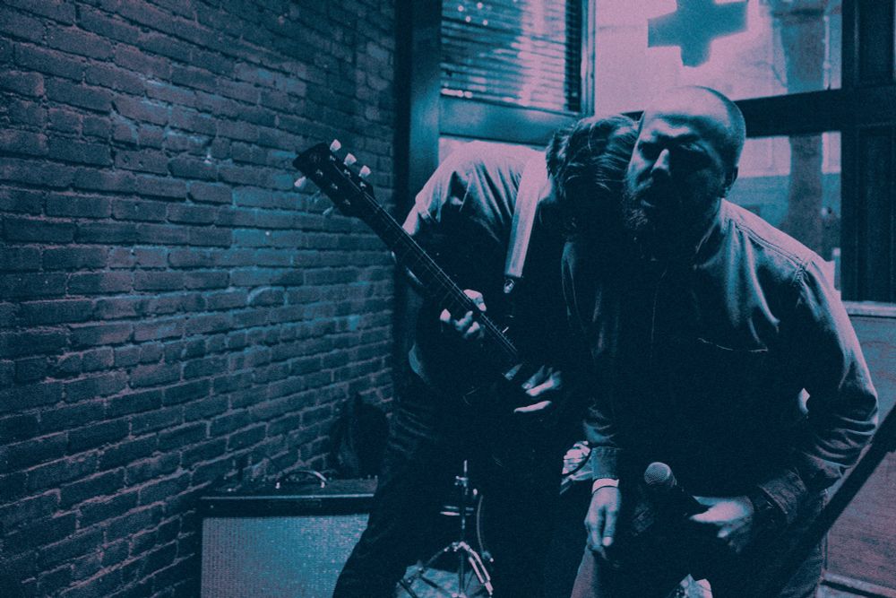 Photos of the band shame chamber playing

Photo of the vocalist and the guitarist leaning on each other and hunched over