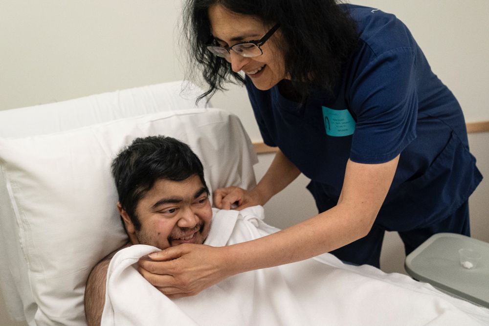 Suneel Ram and his mother, Dr. Neera Gulati, joke around together as Gulati adjusts a blanket around Suneel’s shoulders, visiting Oishei Children’s Hospital for Suneel’s twice-annual bone infusion in Buffalo, July 14, 2024. Suneel receives bone infusions every six months, receiving  zoledronic acid, which helps strengthen his bones, and acetaminophen, through his port. (Libby March/Buffalo News)