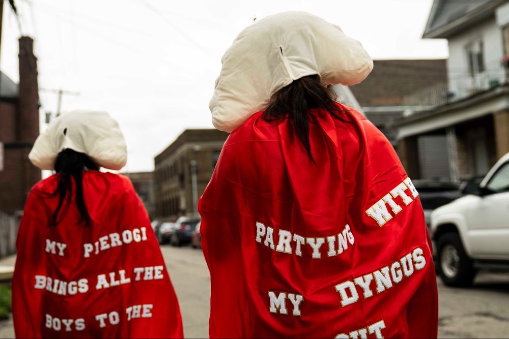 Sally Sanford, left, and her daughter-in-law Kyla Whitford wear pierogi hats and red capes with punny phrases as they walk to Corpus Christi Athletic Club, celebrating Dyngus Day in Buffalo, April 21, 2025. (Libby March/Buffalo News)
