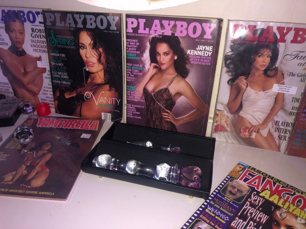 Image of glass heart shaped wand and lined up playboy magazines as a backdrop