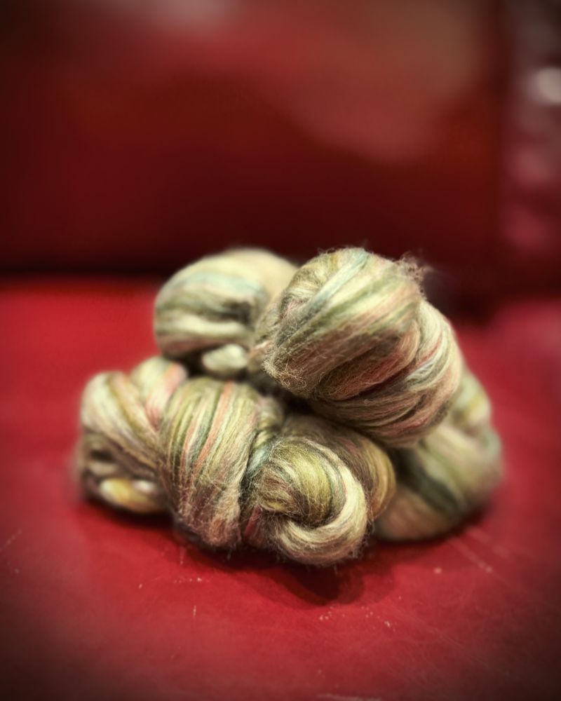 Three bundles of green combed top stacked on a red couch.