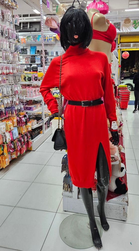 Um manequim feminino com vestido vermelho, cinto preto e peruca preta.