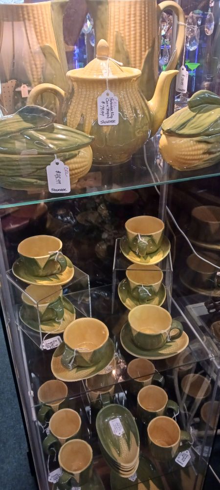 A yellow and green corn themed tea set, every individual item is painted to resemble an ear of corn, including corn shaped plates