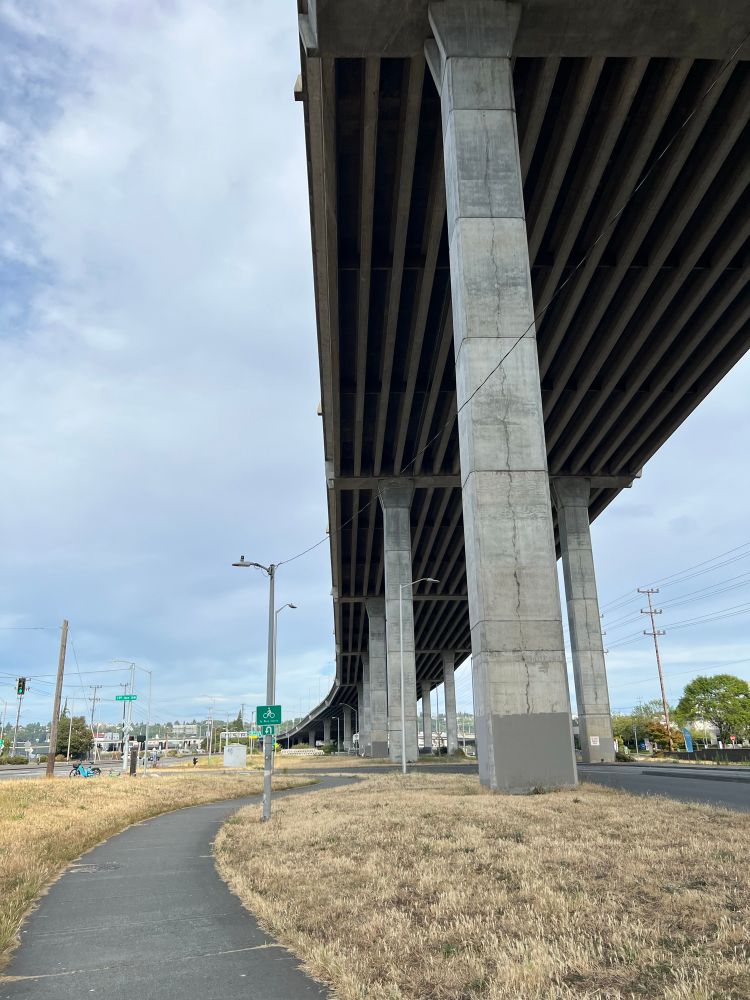 Asphalt trail alongside a massive car viaduct. 