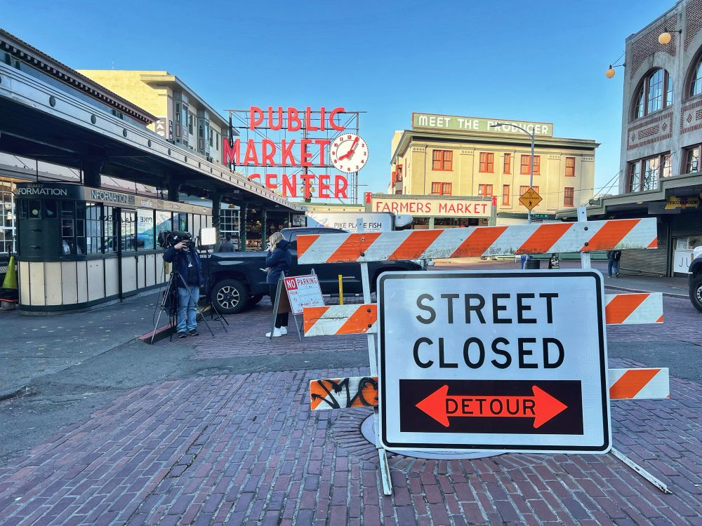 Street closed sign in front of the market. News crew behind. 
