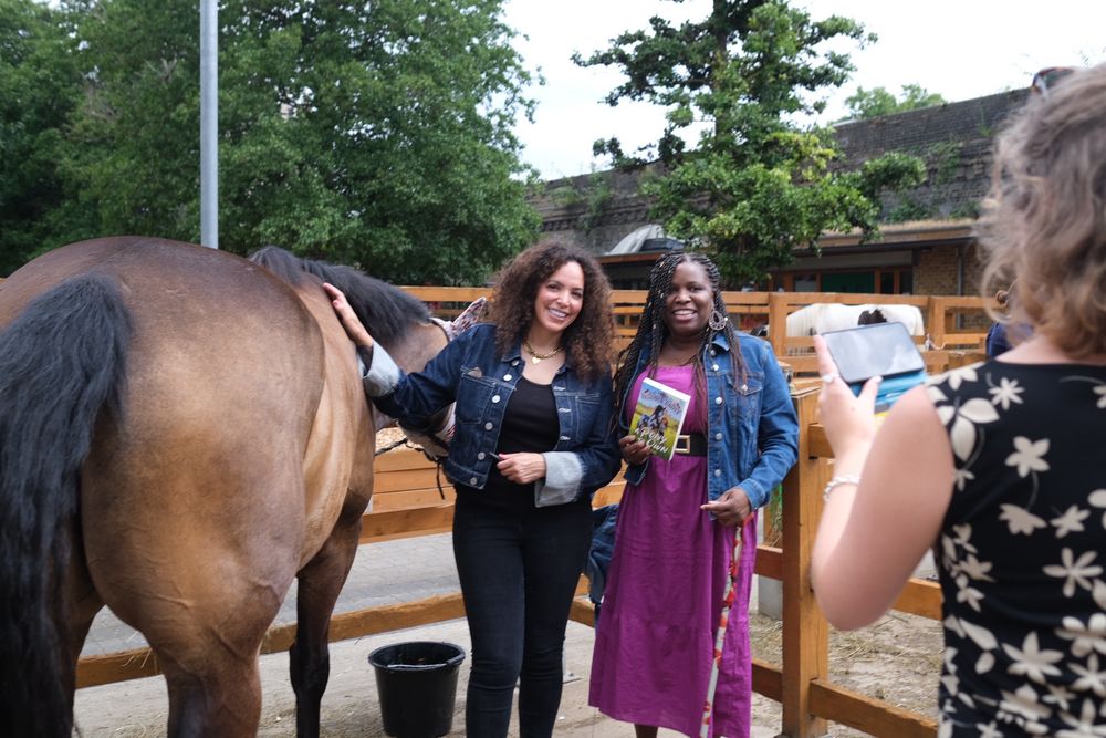 Author JP Rose pets a brown horse. Author/illustrator Antoinette Brooks stands next to her. 