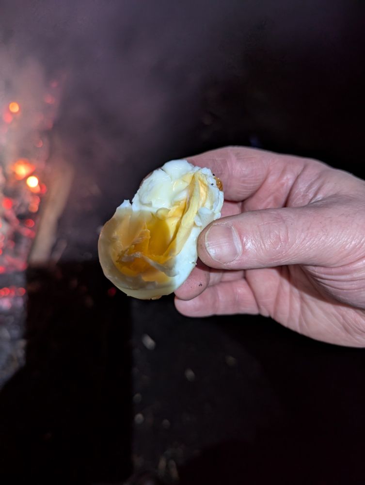 The cooked egg, peeled (and also half eaten). The darker part on the bottom left of the egg is the shadow from the phone camera. The light is from my head torch and I didn't quite have the angles right. The egg is almost hard boiled, although some of the yolk was still soft. 