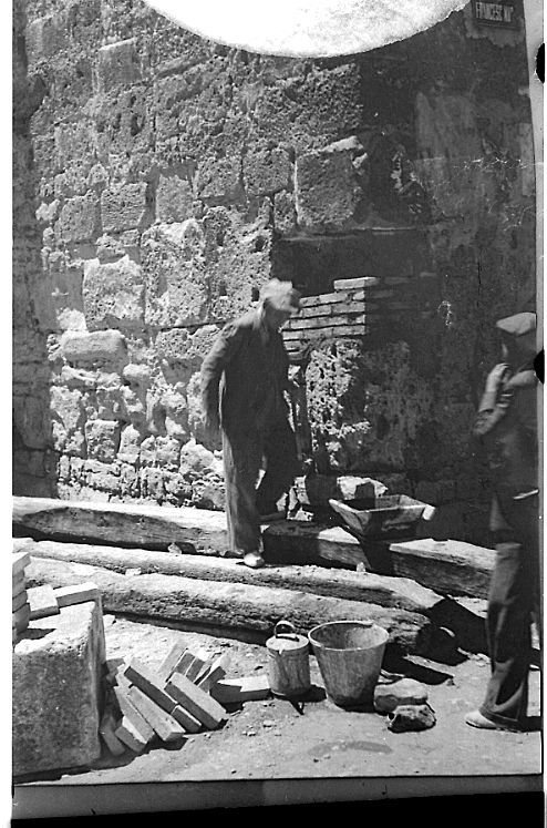 A la fotografia, que descriurem en detall més endavant, s’hi veu un obrer treballant davant d’un edifici. Al terra hi ha diverses eines i material de construcció.
Codi de referència: ACBG30-88-N-1135