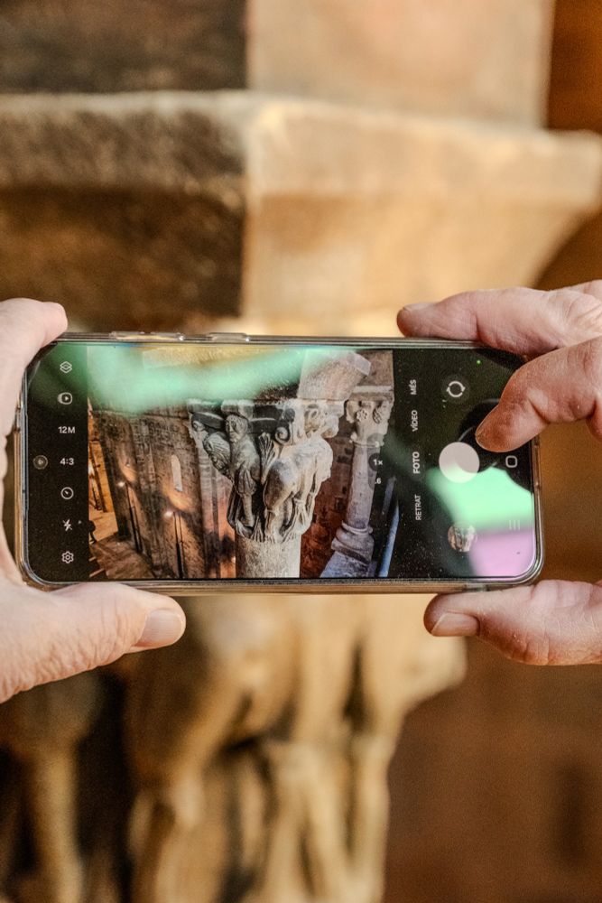 Un visitant fa una foto amb el mòbil a un dels capitells de Santa Maria de Covet.