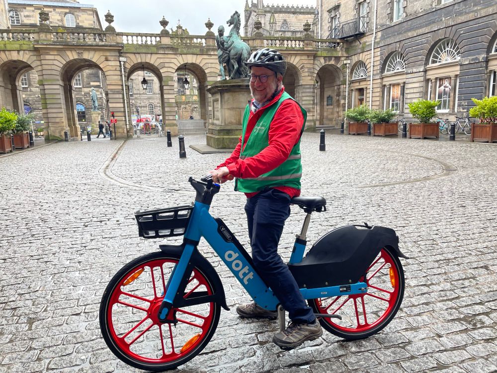 Photo of Chas Booth on a Dott e-bike in the quadrangle at Edinburgh City Chambers. 