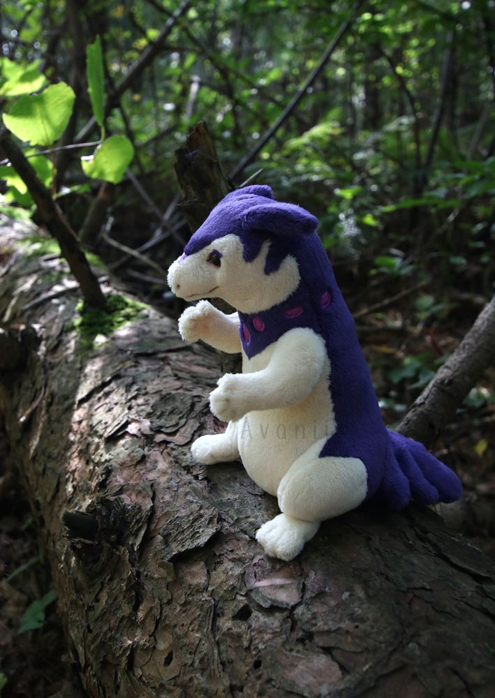 A small plushie hisuian typhlosion sits on a fallen tree, side view