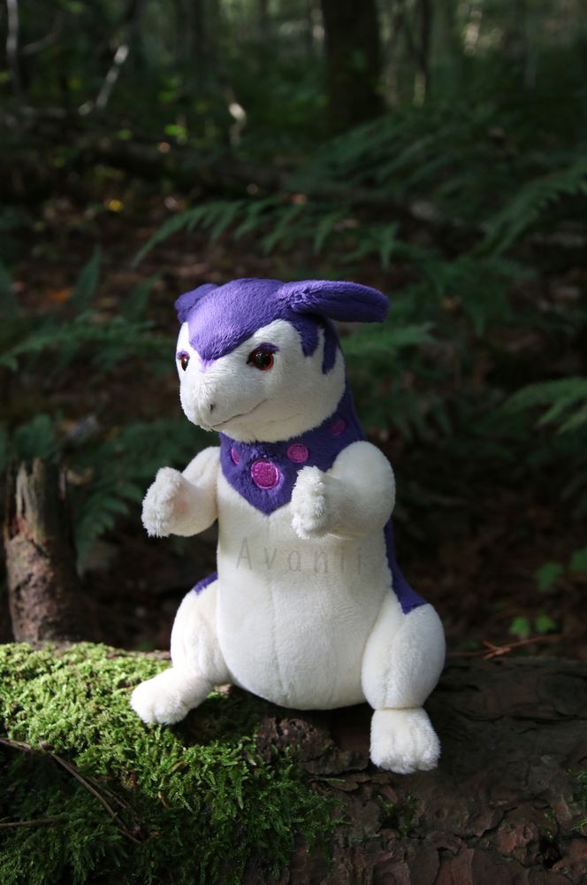 A small hisuian typhlosion plush sits on a wooden branch with both arms raised up
