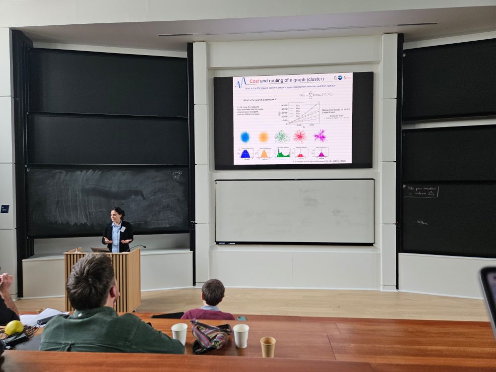 Valentina Parigi presents a talk, standing in front of a slide with complex networks on it.