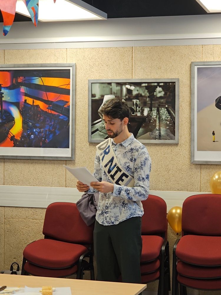 Niels reads a piece of paper with pictures on the background. He is wearing a ribbon that says "Dr Niels"