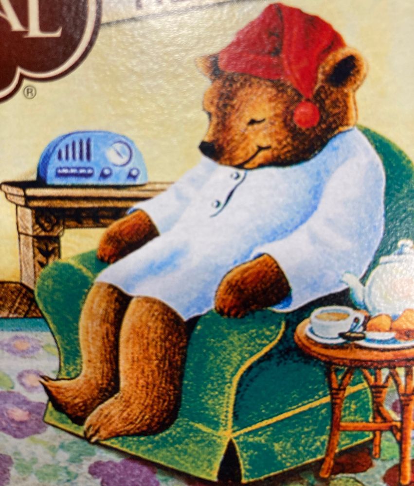 A sleepy bear in pajamas on a cozy green chair 