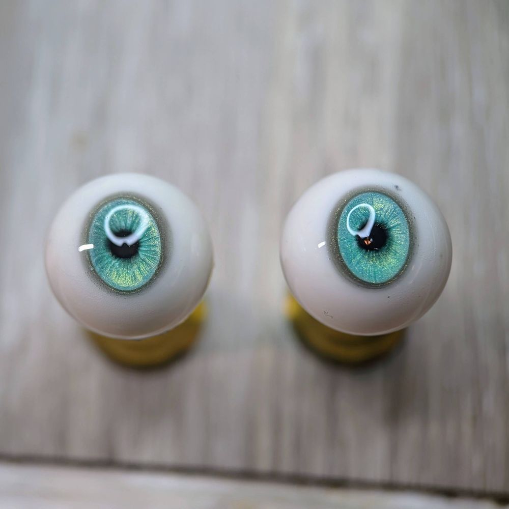 a pair of resin doll eyes with anime-style oval irises in blue-green