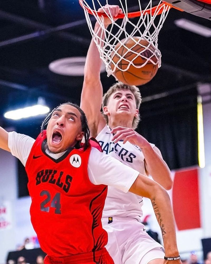 Photo of Johnny Furphy in a white Pacers uniform dunking the ball over Noa Essengue, who is wearing a red Bulls uniform and making an "oh shit" face.