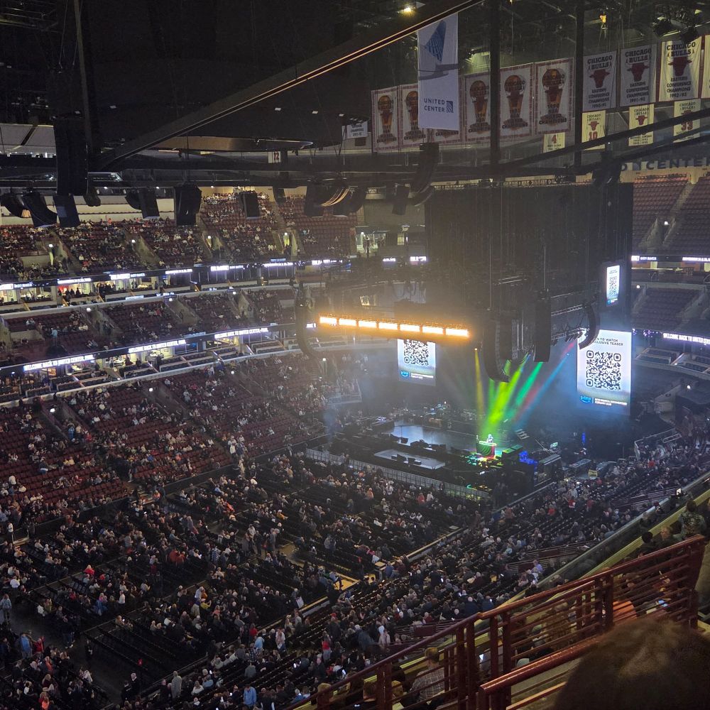 A half full stadium with a lighted stage
