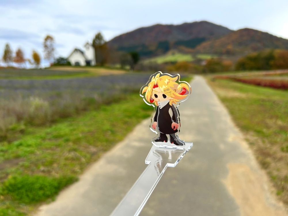 冬のやくらいガーデンと山を背景に創作キャラのアクリルスタンドを掲げた写真