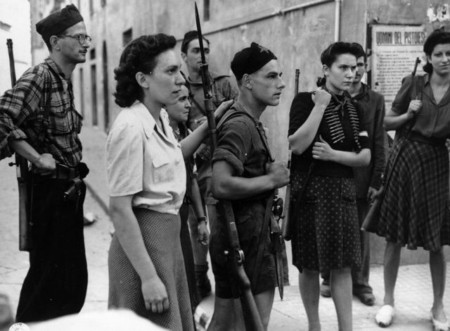 a group of partigiane and partigiani listening attentively 