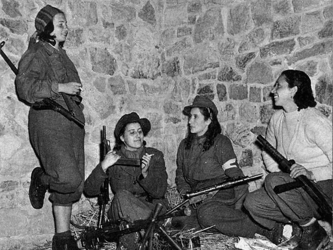 partigiane resting, chatting and smoking between the fighting, with their rifles next to them