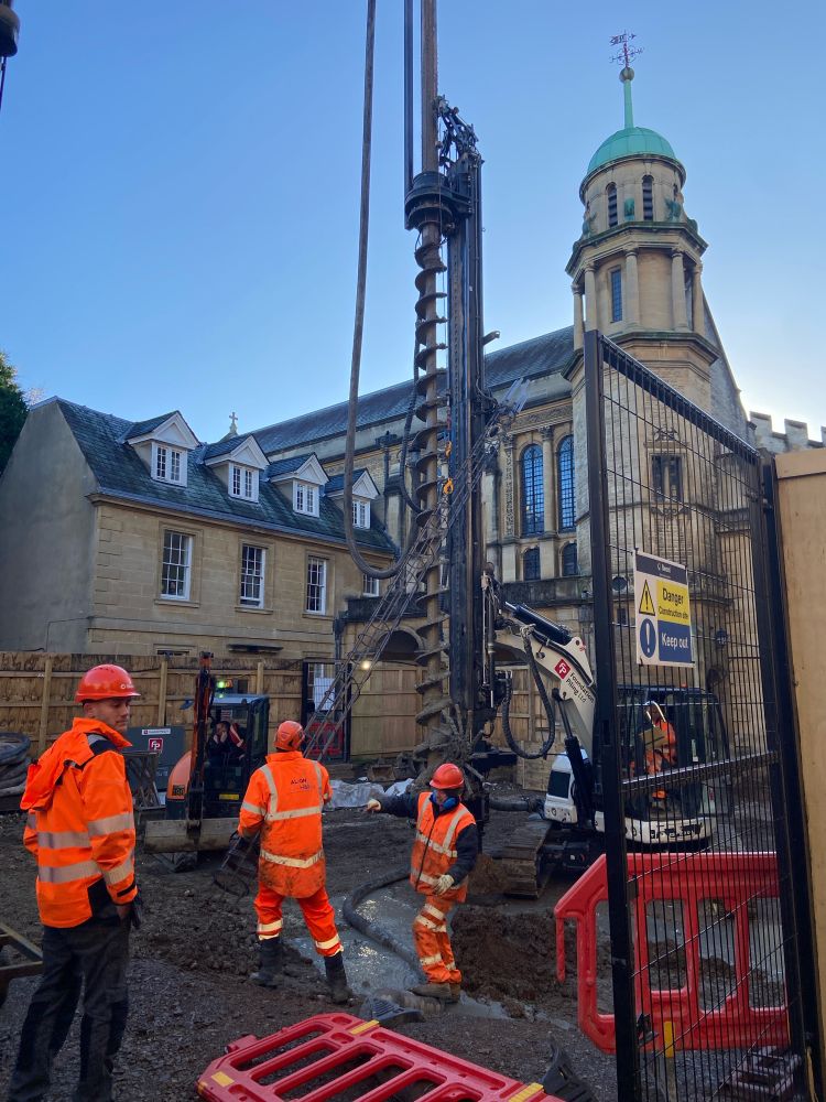 Construction workers operating pile  driver machinery