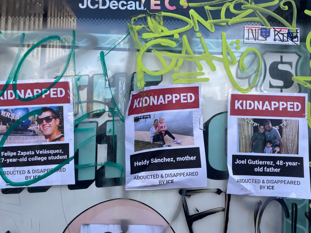 Three posters on a a graffitied bus stop, each with information about a person “abducted and disappeared by ICE”