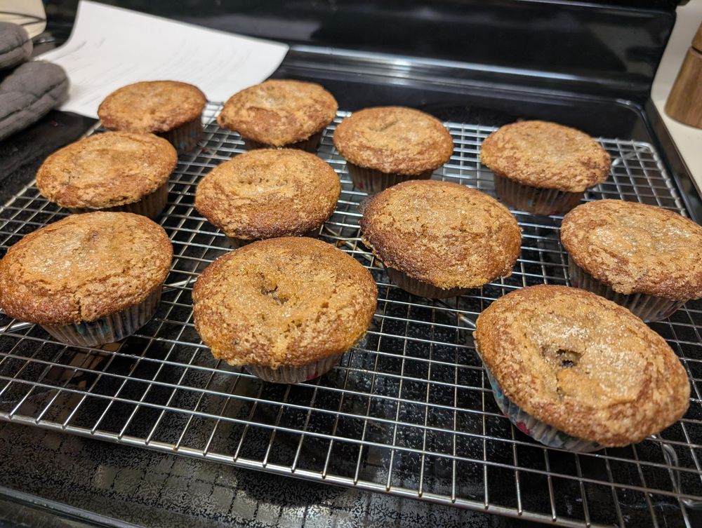 Cooling rack of 12 muffins. They have slightly sunken but crispy centers from being topped with sugar before baking!