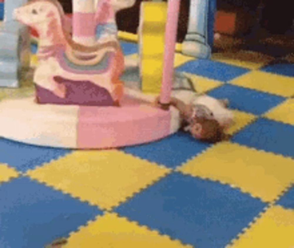 a child is laying on the floor in front of a carousel .