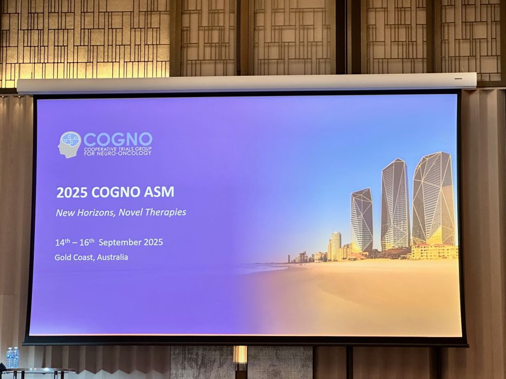 An image featuring a screen with a slide. There is an image in the background of the Gold Coast, and text reading 2025 COGNO ASM New Horizons, Novel Therapies 14 - 16 September 2025, Gold Coast, Australia