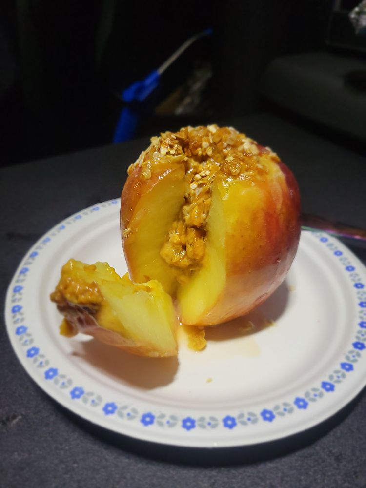 The cross section of a baked apple dripping with caramel, oats, honey and peanut butter