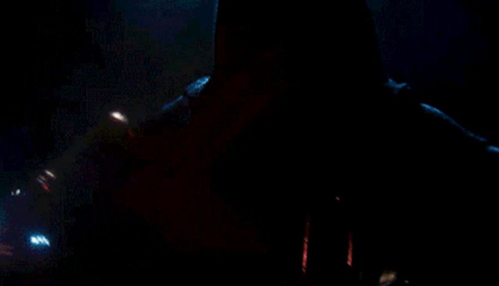 a close up of a person holding a red light saber in the dark