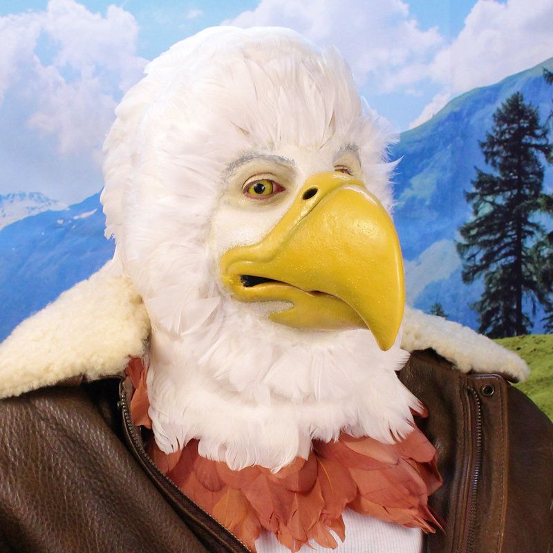 A man wearing prosthetic makeup to resemble an anthropomorphic bald eagle with feathers on his head and wearing a leather bomber jacket.
