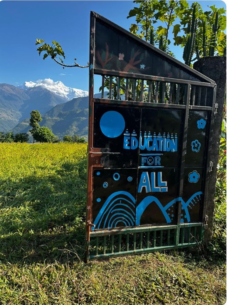 Sign “Education for all on a plot if land against the backdrop of a mountain range in Nepal