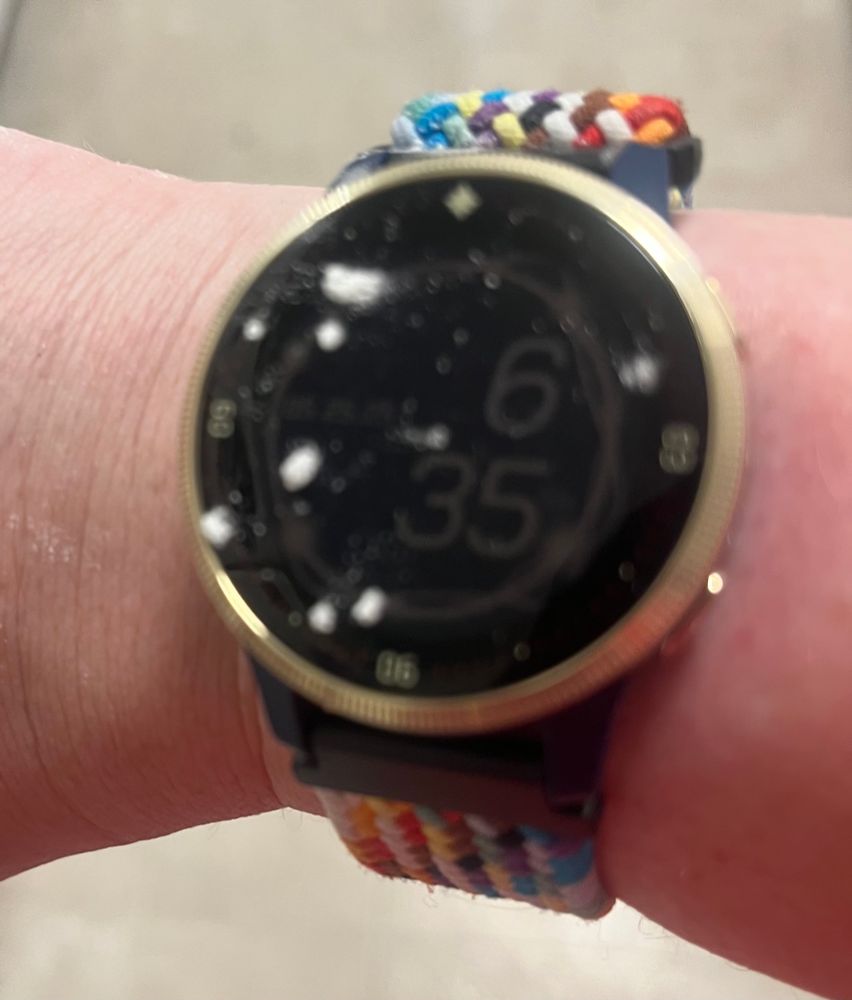 A white person’s arm with a digital watch face reading 6:30pm. There are several prominent splatters of confectioners sugar on the watch face. 