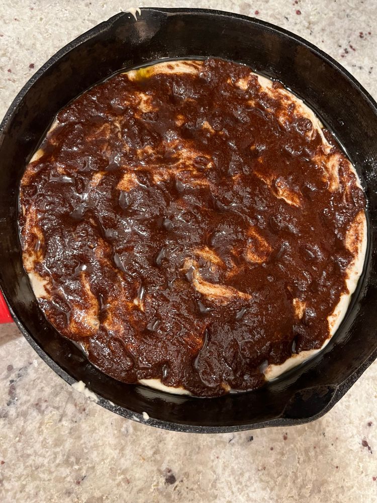 Cast iron skillet with focaccia dough covered in a cinnamon sugar mixture