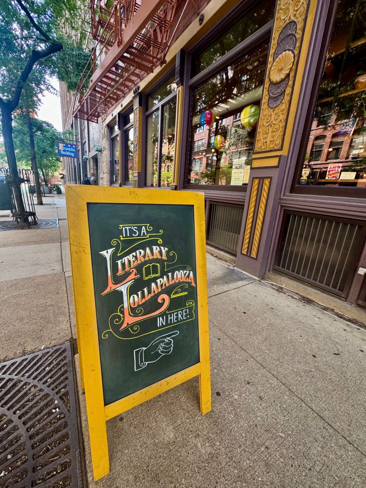 A sign in front of Sandmeyer’s bookstore that says “it’s a Literary Lollapalooza in here” 
