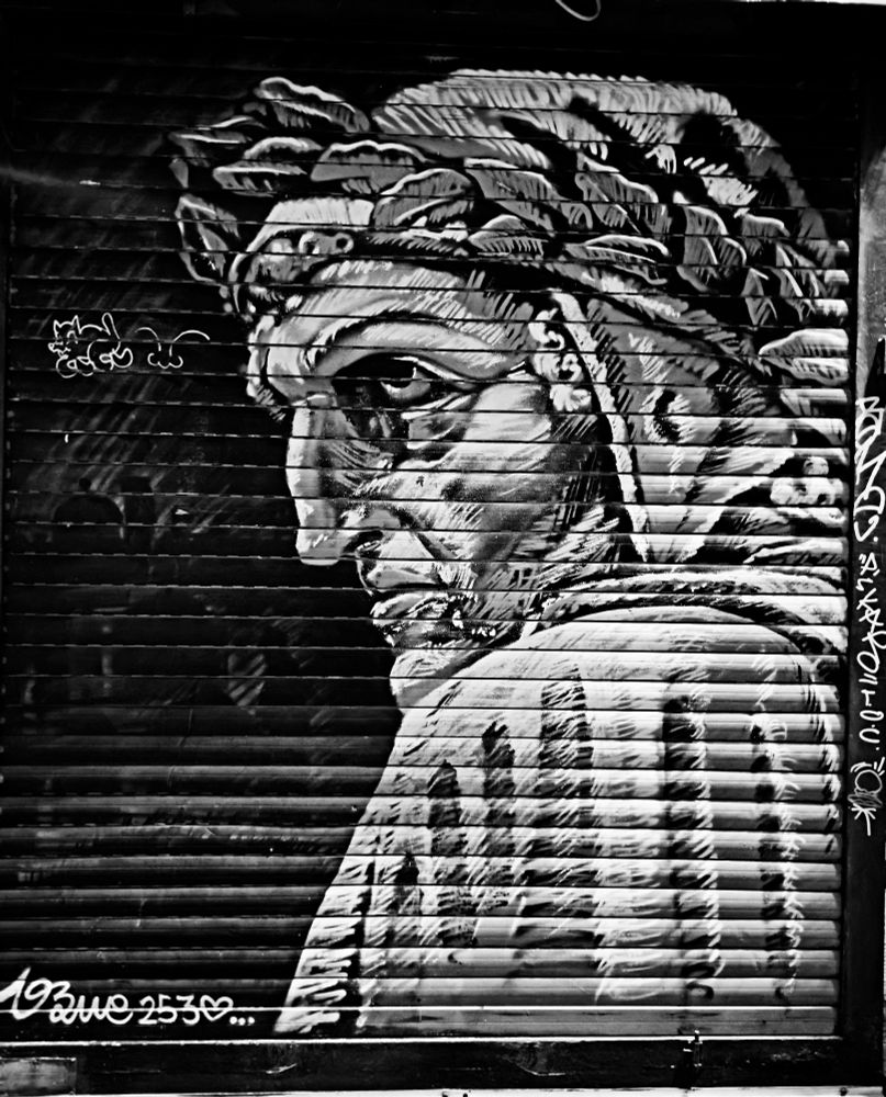 A street art mural of Dante's face painted on a kiosk shutter in Florence, Italy. 