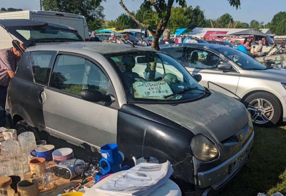 Beat up french car with sign in front window saying the indicators don't work