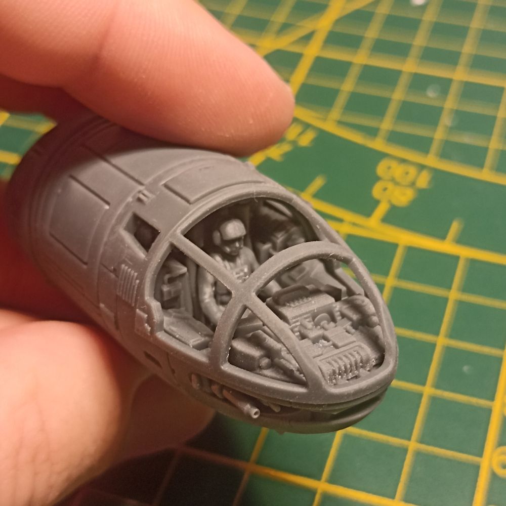 Photo du cockpit d'un vaisseau spatial imprimé en 3D. Il a une forme un peu ovoïde. Derrière la canopée, on voit la pilote au milieu d'un t'as d'ordinateur de navigation 